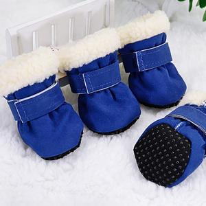 Set of four blue dog boots with white fleece lining and non-slip black soles on white carpet