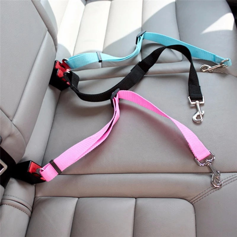Adjustable pet car seat belt harness in pink, black, and blue on gray leather car seat