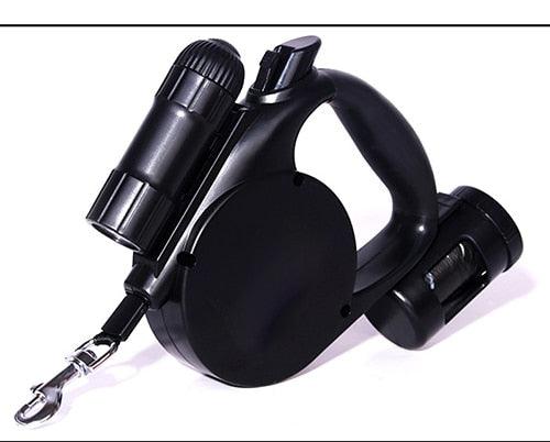 Black retractable dog leash with ergonomic handle and attached waste bag dispensers on white background