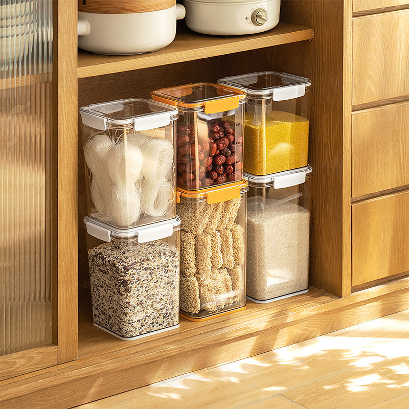 Stacked clear plastic airtight food storage containers with garlic, dried berries, grains, and pasta in wooden kitchen cabinet