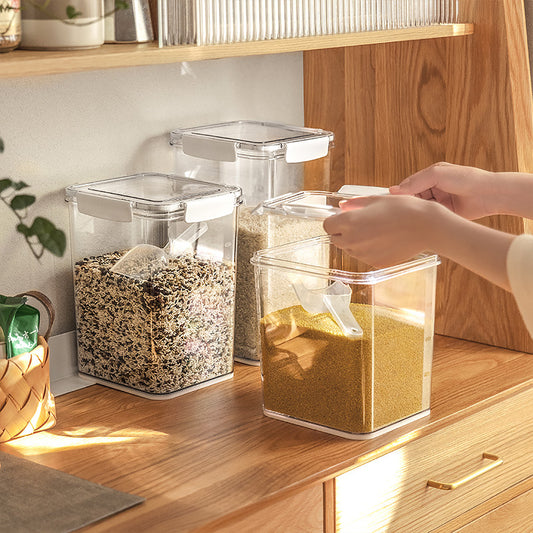 Transparent airtight food storage containers with white lids holding grains and spices on a wooden kitchen countertop